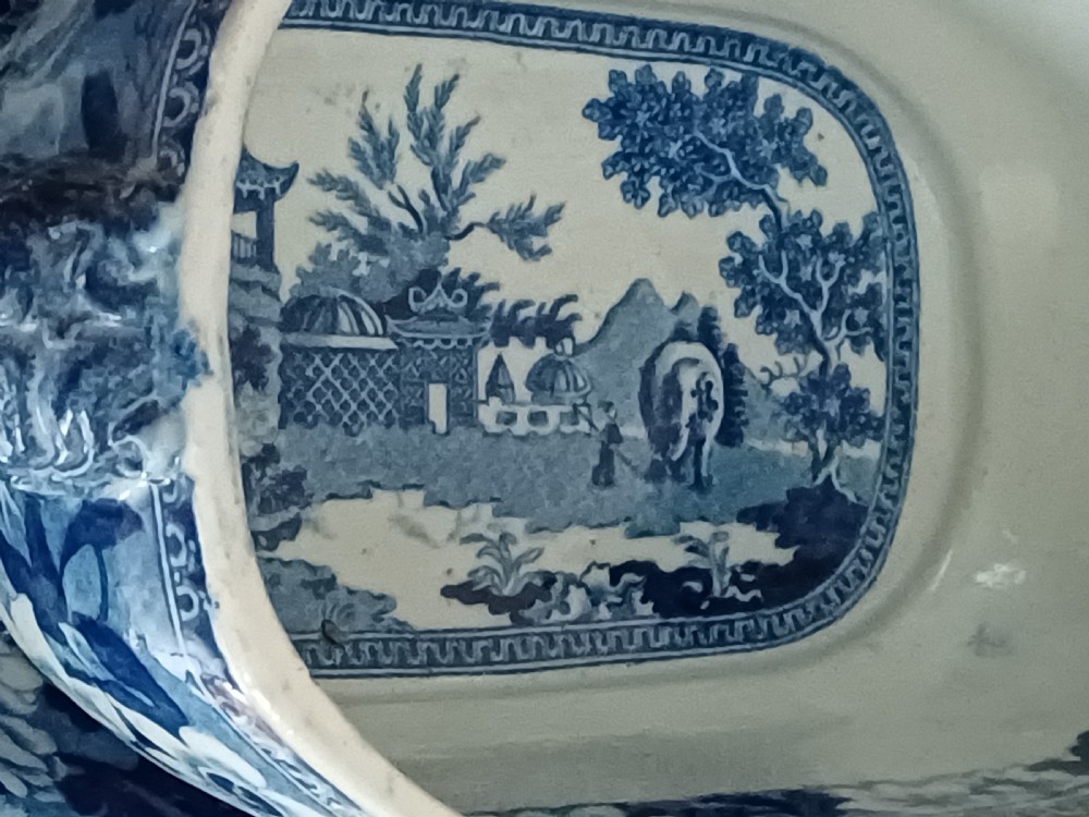 A Georgian blue and white transfer-printed ceramic sauce tureen featuring floral patterns, lion head side handles, a lion finial lid, and a matching underplate. View VI