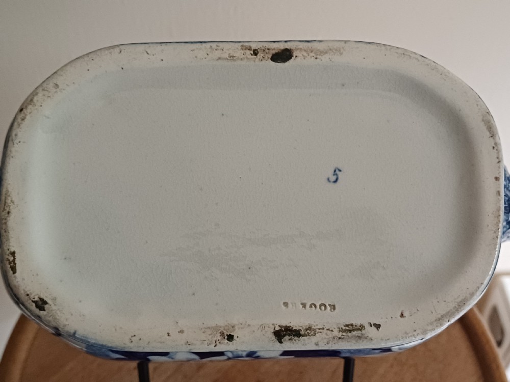 A Georgian blue and white transfer-printed ceramic sauce tureen featuring floral patterns, lion head side handles, a lion finial lid, and a matching underplate. View XII