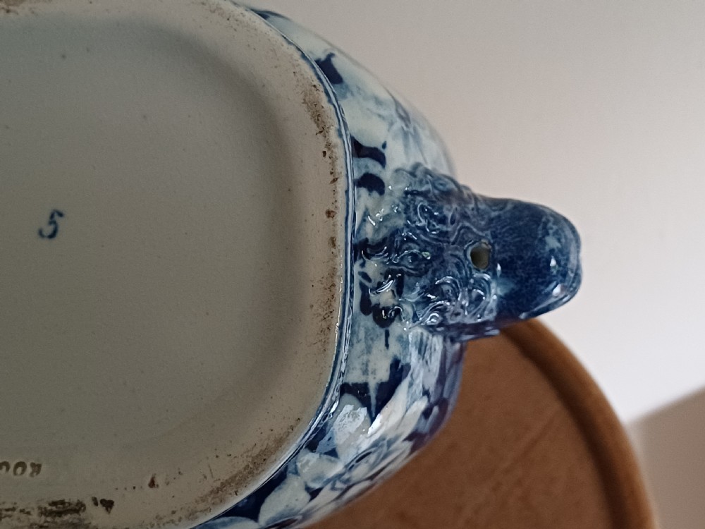 A Georgian blue and white transfer-printed ceramic sauce tureen featuring floral patterns, lion head side handles, a lion finial lid, and a matching underplate. View XIV