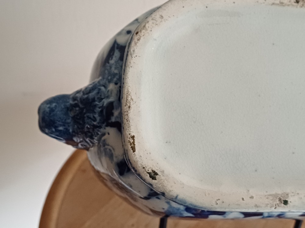 A Georgian blue and white transfer-printed ceramic sauce tureen featuring floral patterns, lion head side handles, a lion finial lid, and a matching underplate. View XV