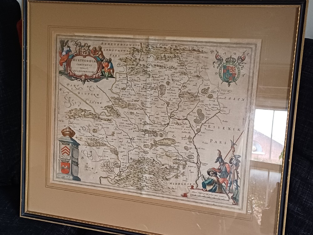 A framed 17th-century hand-coloured map of Hertfordshire by cartographer Jan Blaeu featuring decorative heraldic coats of arms and a title cartouche.