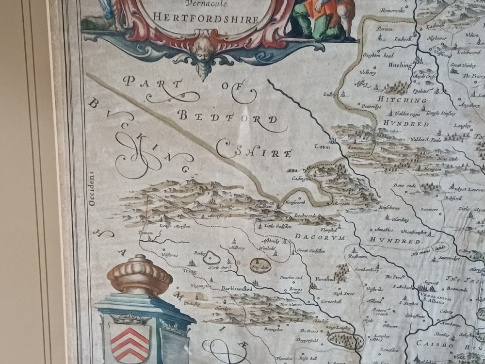 A framed 17th-century hand-coloured map of Hertfordshire by cartographer Jan Blaeu featuring decorative heraldic coats of arms and a title cartouche. View V
