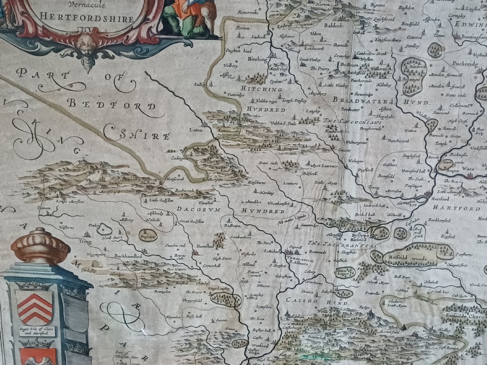 A framed 17th-century hand-coloured map of Hertfordshire by cartographer Jan Blaeu featuring decorative heraldic coats of arms and a title cartouche. View X