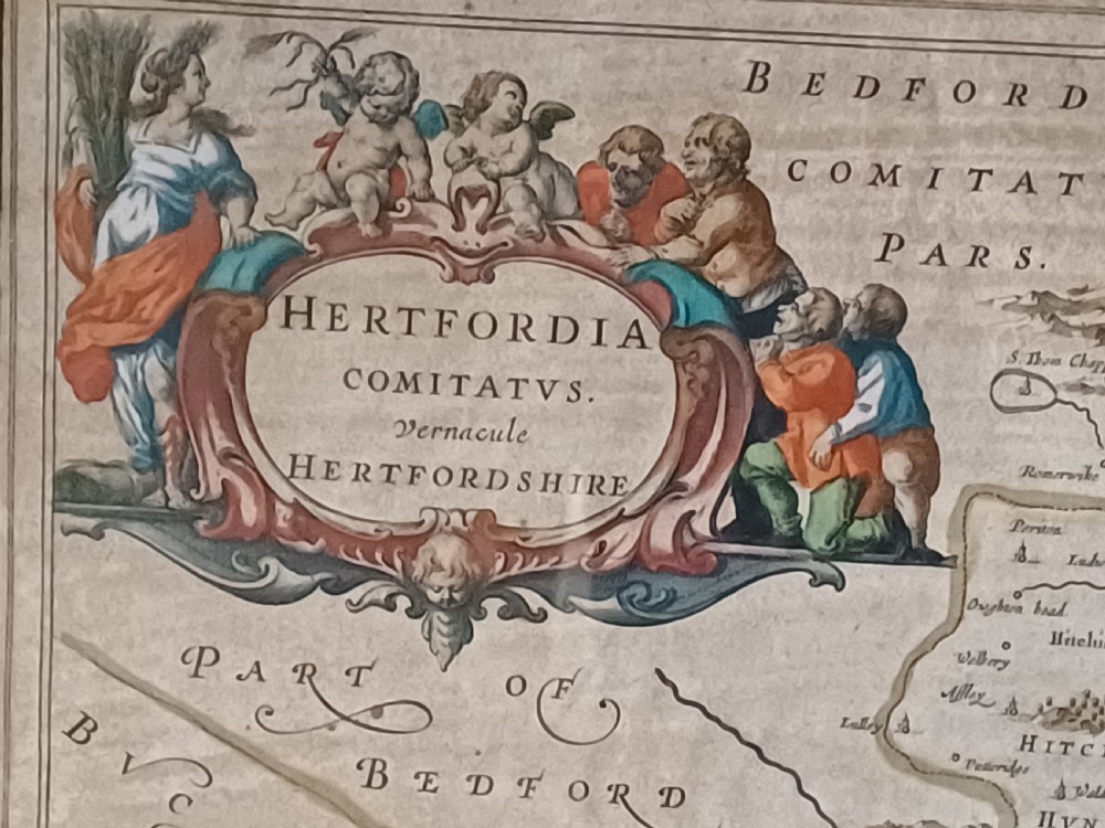 A framed 17th-century hand-coloured map of Hertfordshire by cartographer Jan Blaeu featuring decorative heraldic coats of arms and a title cartouche. View XII