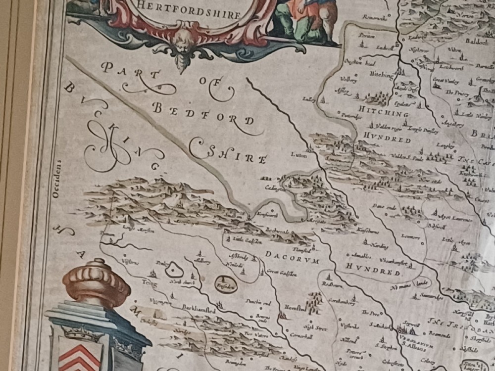 A framed 17th-century hand-coloured map of Hertfordshire by cartographer Jan Blaeu featuring decorative heraldic coats of arms and a title cartouche. View XV
