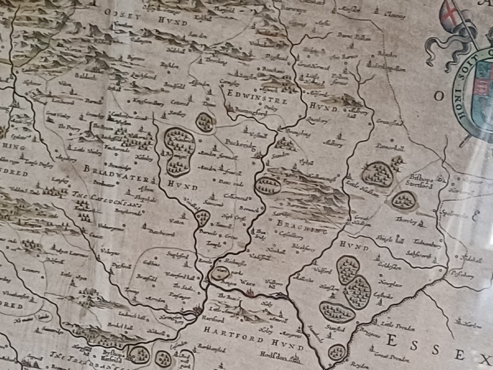 A framed 17th-century hand-coloured map of Hertfordshire by cartographer Jan Blaeu featuring decorative heraldic coats of arms and a title cartouche. View XVI