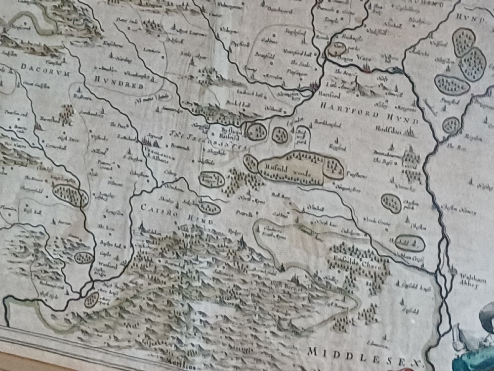 A framed 17th-century hand-coloured map of Hertfordshire by cartographer Jan Blaeu featuring decorative heraldic coats of arms and a title cartouche. View XVII