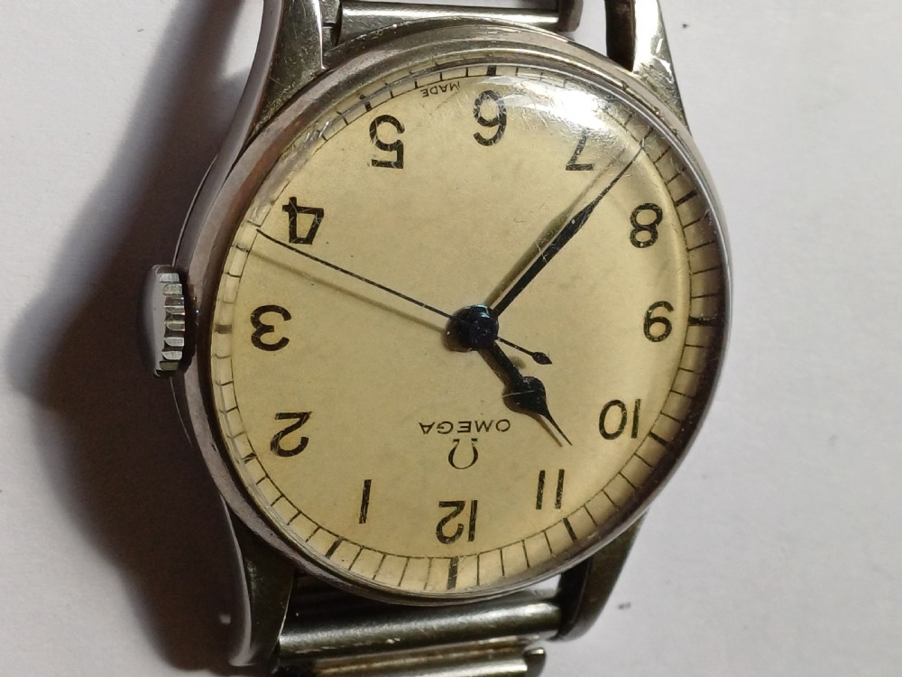Vintage Omega 6B159 military pilot wristwatch with a cream dial, Arabic numerals, and a stainless steel case. View VII