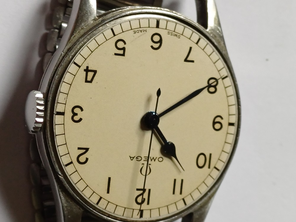 Vintage Omega 6B159 military pilot wristwatch with a cream dial, Arabic numerals, and a stainless steel case. View IX