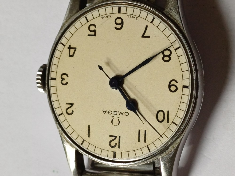 Vintage Omega 6B159 military pilot wristwatch with a cream dial, Arabic numerals, and a stainless steel case. View X