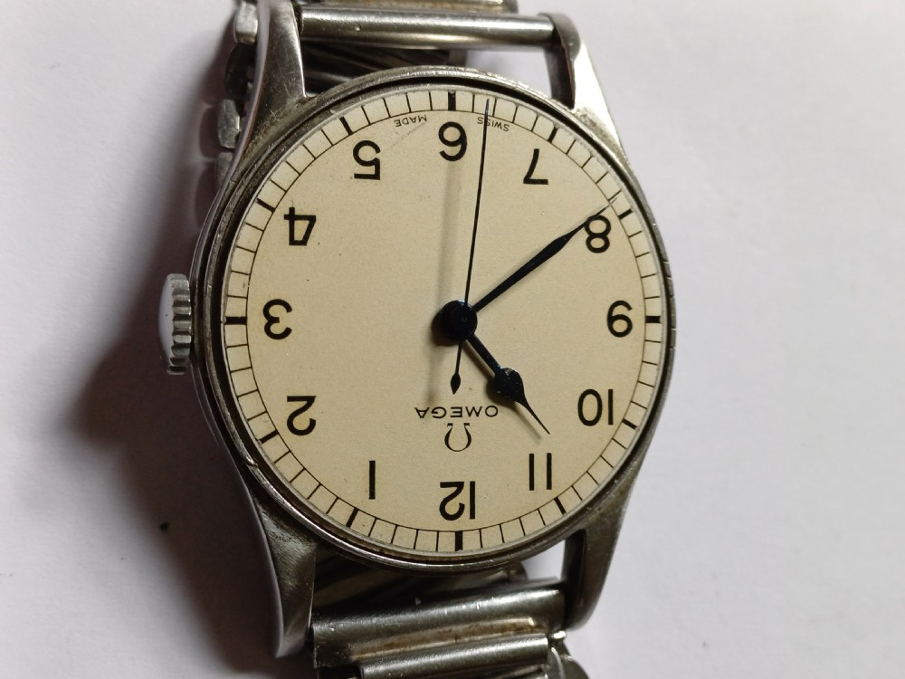Vintage Omega 6B159 military pilot wristwatch with a cream dial, Arabic numerals, and a stainless steel case. View XII