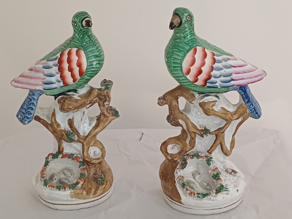 Reserved AD A rare pair of Staffordshire figures of a bird, possibly a pigeon or dove, seated on a tree with a nest of eggs below. Each one is brightly painted and dating circa 1860