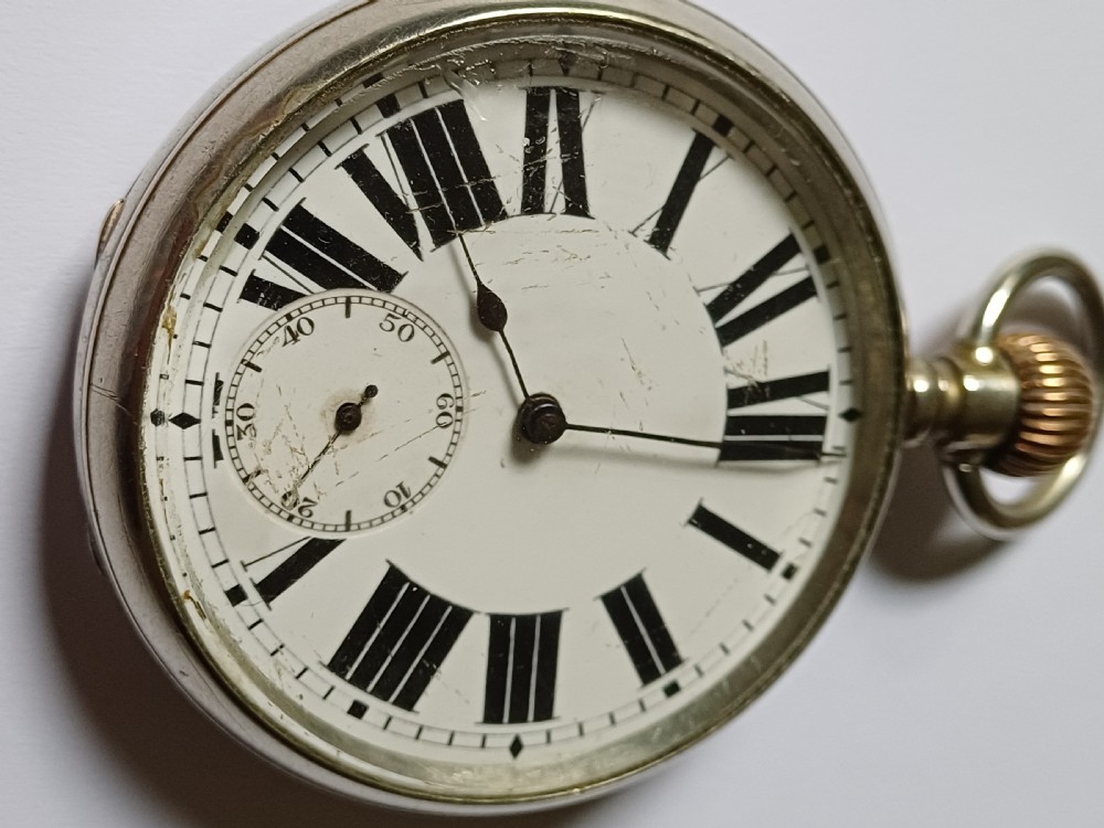An antique open-face silver pocket watch featuring a white enamel dial with bold black Roman numerals and a subsidiary seconds dial.