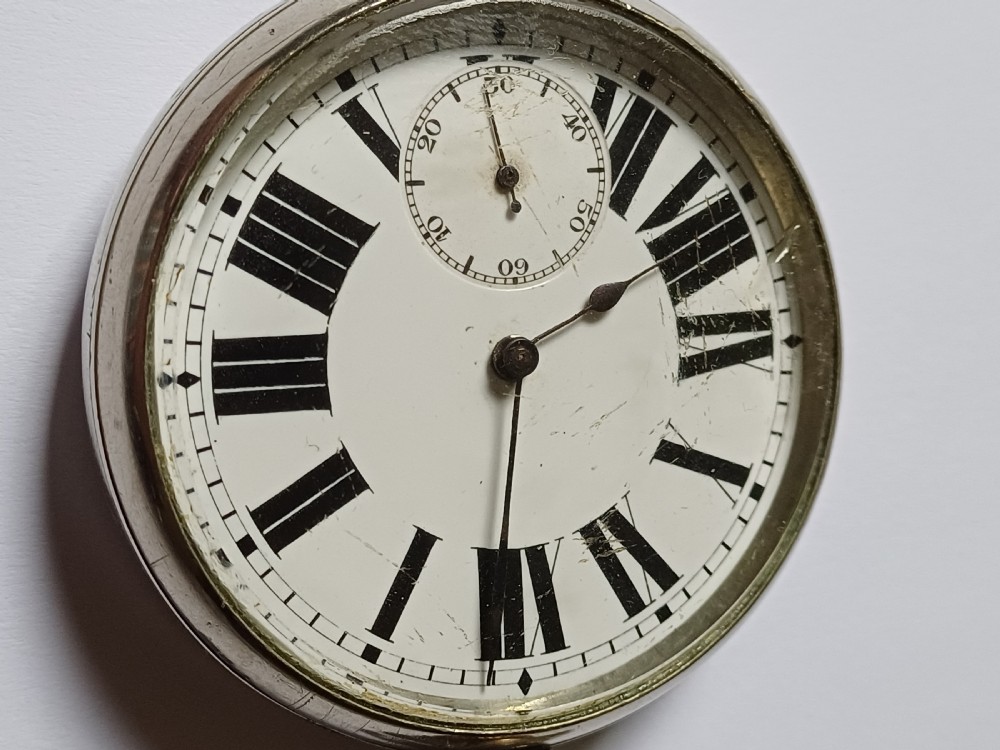 An antique open-face silver pocket watch featuring a white enamel dial with bold black Roman numerals and a subsidiary seconds dial. View II