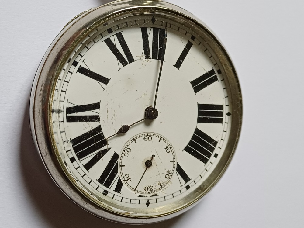 An antique open-face silver pocket watch featuring a white enamel dial with bold black Roman numerals and a subsidiary seconds dial. View IV