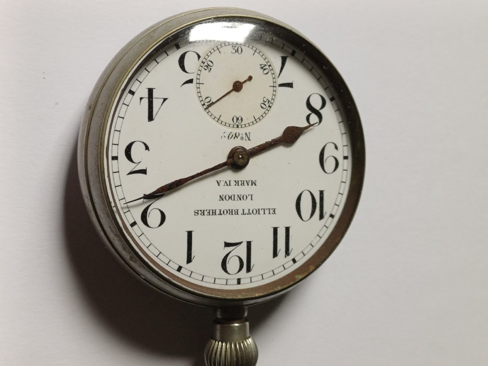 An antique First World War era military pocket watch with a white enamel dial, black Arabic numerals, and a nickel-plated metal case. View II