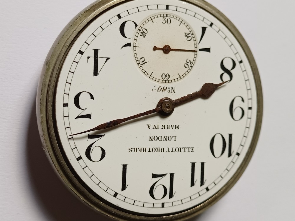 An antique First World War era military pocket watch with a white enamel dial, black Arabic numerals, and a nickel-plated metal case. View IV