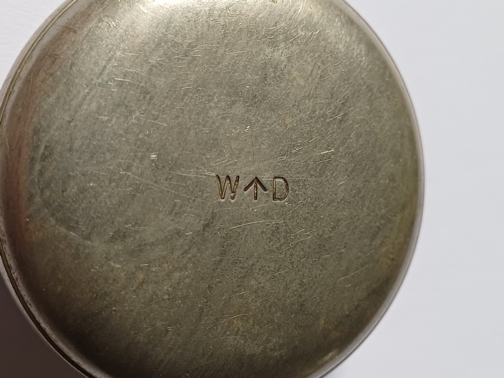 An antique First World War era military pocket watch with a white enamel dial, black Arabic numerals, and a nickel-plated metal case. View XI