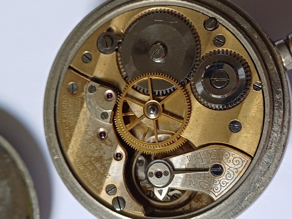 An antique First World War era military pocket watch with a white enamel dial, black Arabic numerals, and a nickel-plated metal case. View XIV