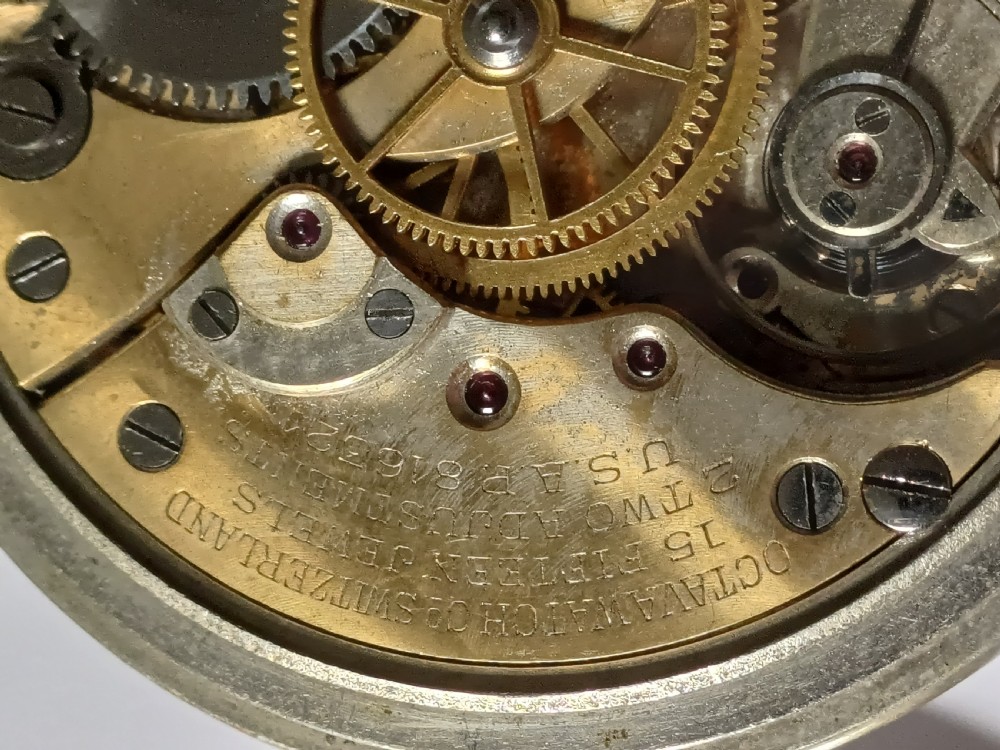 An antique First World War era military pocket watch with a white enamel dial, black Arabic numerals, and a nickel-plated metal case. View XV