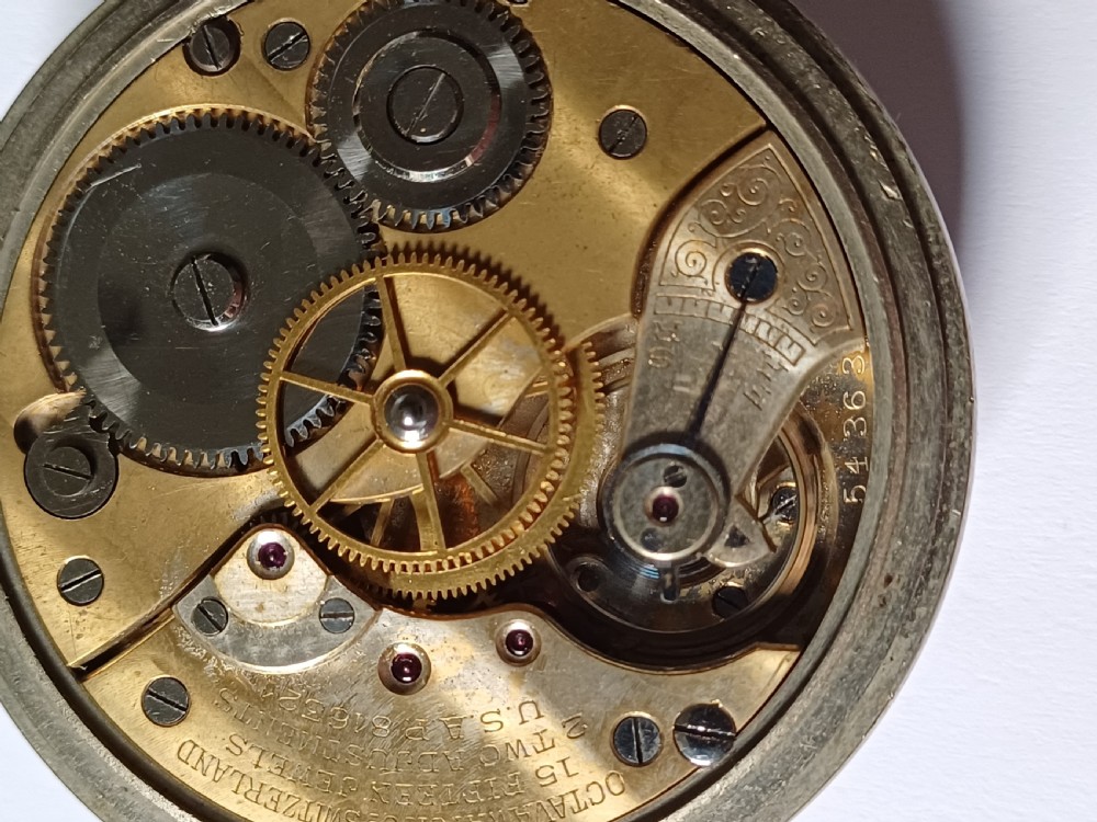An antique First World War era military pocket watch with a white enamel dial, black Arabic numerals, and a nickel-plated metal case. View XVI