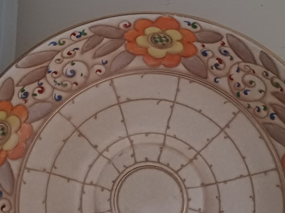 A round Art Deco earthenware bowl featuring a central circular spider-web trellis design surrounded by tube-lined floral motifs in orange and beige. View VIII