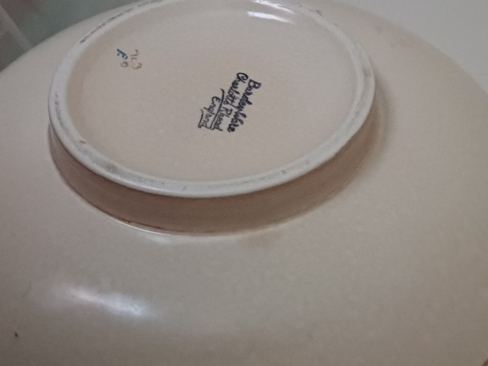 A round Art Deco earthenware bowl featuring a central circular spider-web trellis design surrounded by tube-lined floral motifs in orange and beige. View XII