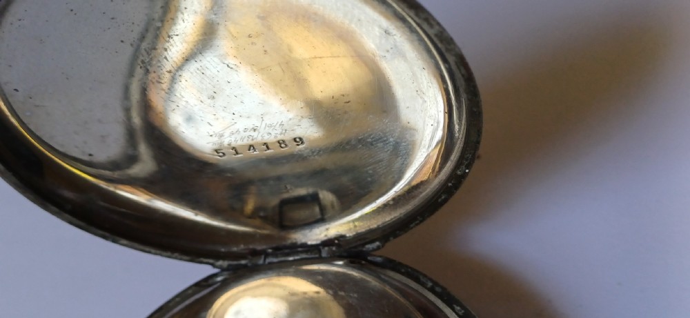 An open-face pocket watch featuring a black dial, luminescent white Arabic numerals, two sub-dials, and a silver-coloured metal case with an onion crown. View VII
