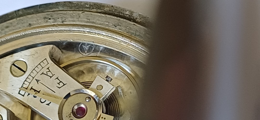 An open-face pocket watch featuring a black dial, luminescent white Arabic numerals, two sub-dials, and a silver-coloured metal case with an onion crown. View XI