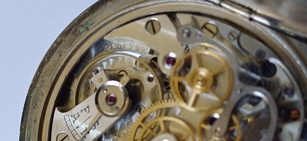 An open-face pocket watch featuring a black dial, luminescent white Arabic numerals, two sub-dials, and a silver-coloured metal case with an onion crown. View XIII