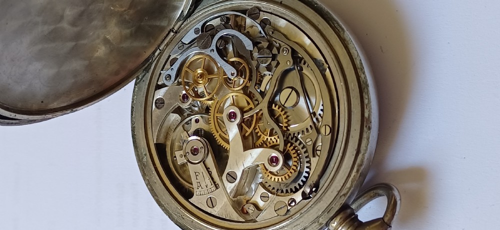 An open-face pocket watch featuring a black dial, luminescent white Arabic numerals, two sub-dials, and a silver-coloured metal case with an onion crown. View XIV