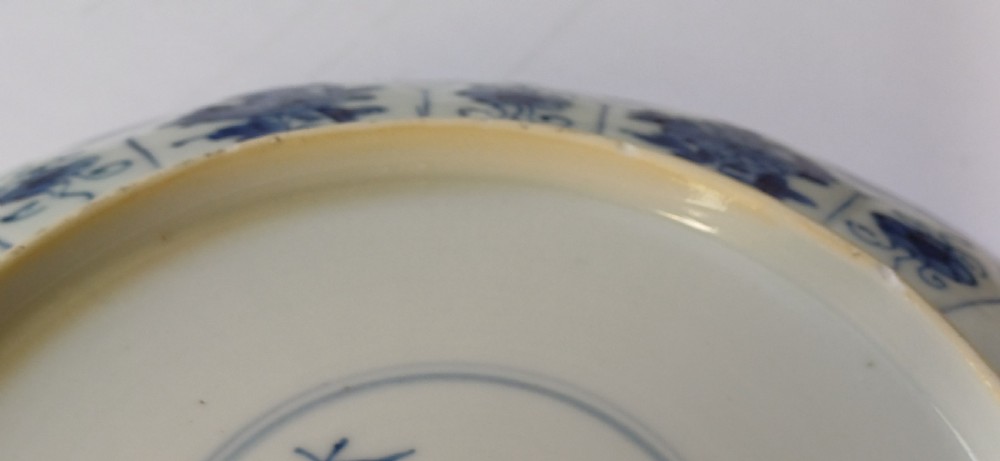 A circular Chinese porcelain dish painted with blue cobalt floral motifs, featuring a barbed rim and radiating moulded petal panels. View V