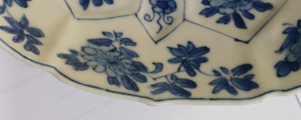 A circular Chinese porcelain dish painted with blue cobalt floral motifs, featuring a barbed rim and radiating moulded petal panels. View X