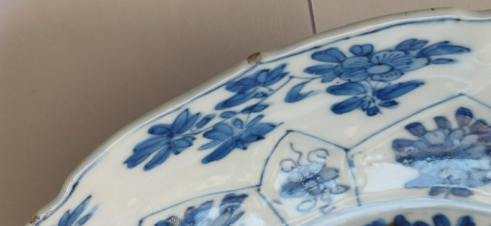 A circular Chinese porcelain dish painted with blue cobalt floral motifs, featuring a barbed rim and radiating moulded petal panels. View XII