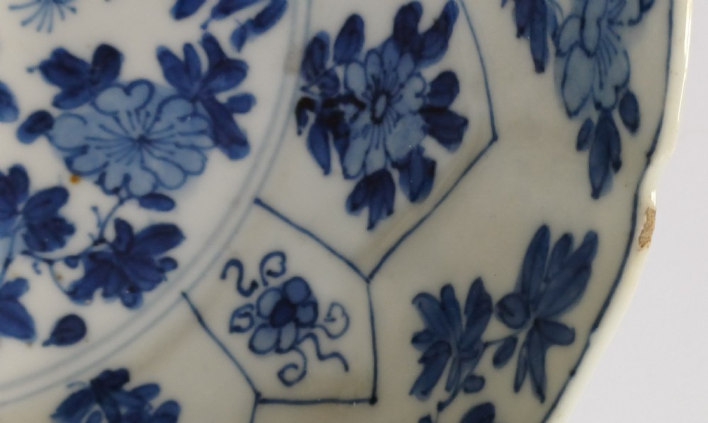 A circular Chinese porcelain dish painted with blue cobalt floral motifs, featuring a barbed rim and radiating moulded petal panels. View XV