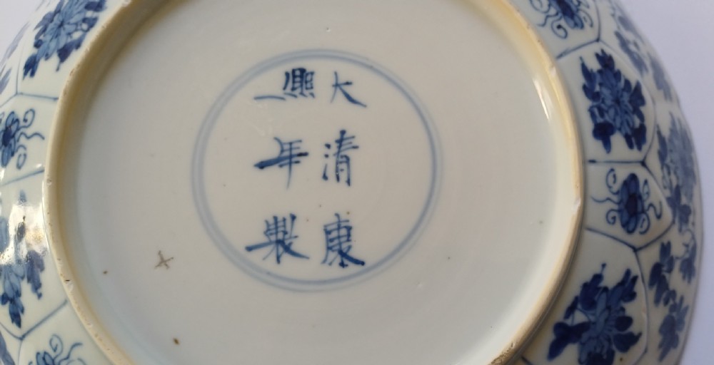 A circular Chinese porcelain dish painted with blue cobalt floral motifs, featuring a barbed rim and radiating moulded petal panels. View XVI
