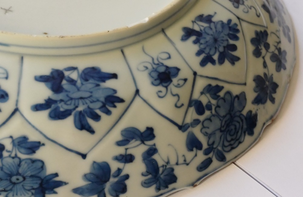 A circular Chinese porcelain dish painted with blue cobalt floral motifs, featuring a barbed rim and radiating moulded petal panels. View XVII