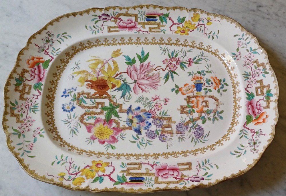 An early Victorian rectangular earthenware platter featuring hand-painted floral motifs in enamel and gilt trim on a scalloped cream ground.