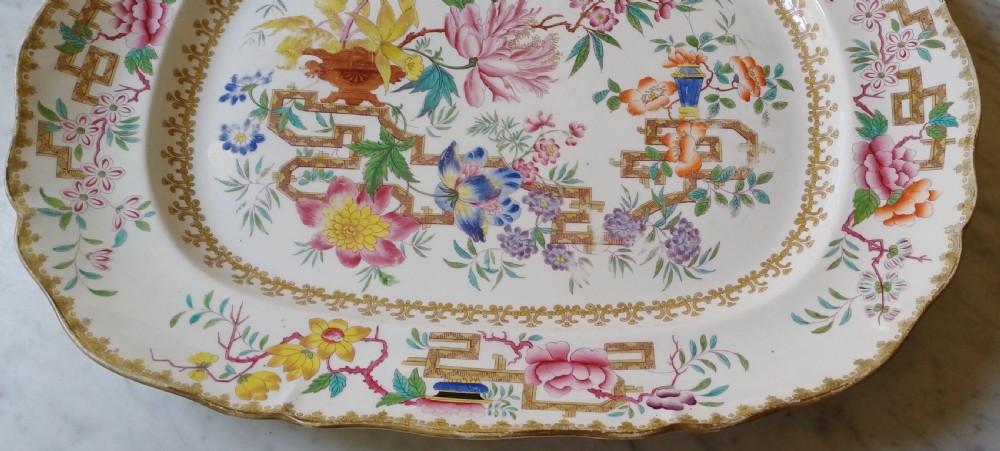 An early Victorian rectangular earthenware platter featuring hand-painted floral motifs in enamel and gilt trim on a scalloped cream ground. View IV