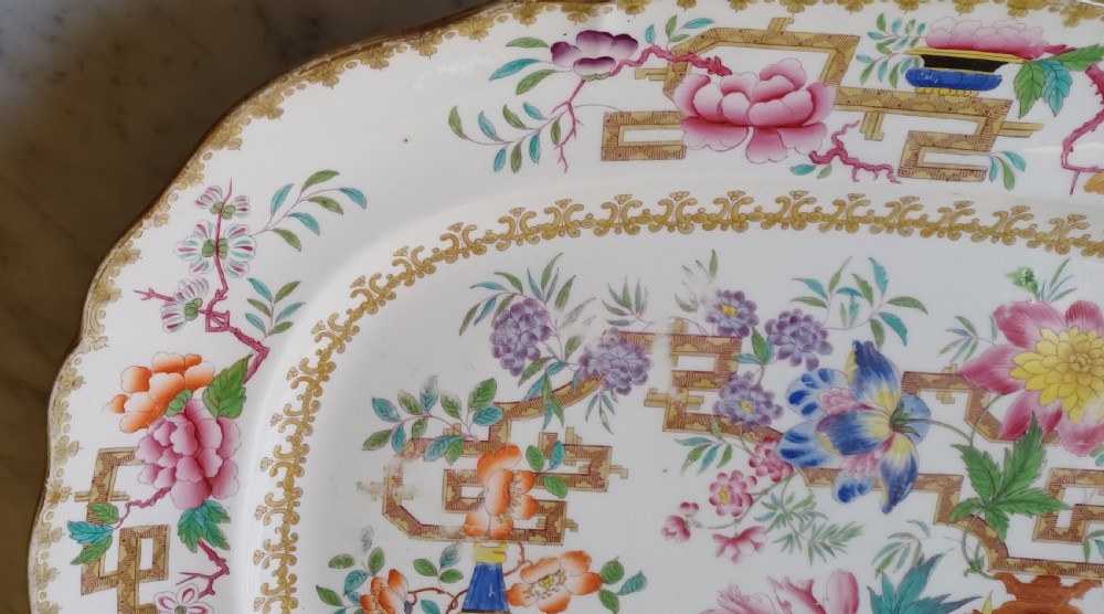 An early Victorian rectangular earthenware platter featuring hand-painted floral motifs in enamel and gilt trim on a scalloped cream ground. View V