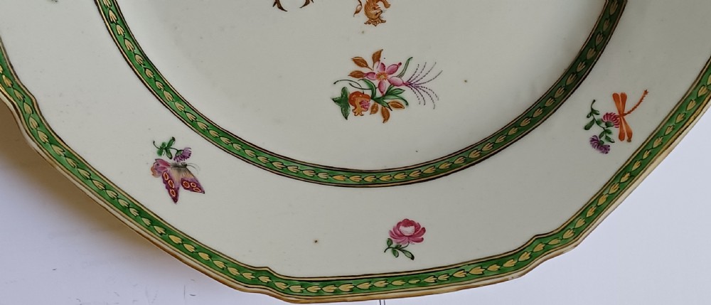 An octagonal 18th-century Chinese export porcelain plate decorated with a central heraldic coat of arms, floral sprays, and a green patterned border. View V