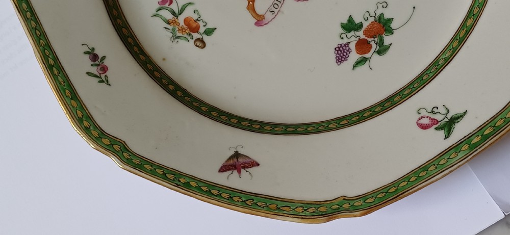 An octagonal 18th-century Chinese export porcelain plate decorated with a central heraldic coat of arms, floral sprays, and a green patterned border. View VII