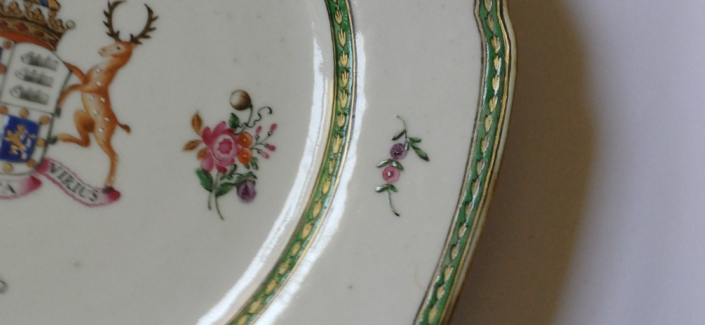 An octagonal 18th-century Chinese export porcelain plate decorated with a central heraldic coat of arms, floral sprays, and a green patterned border. View X