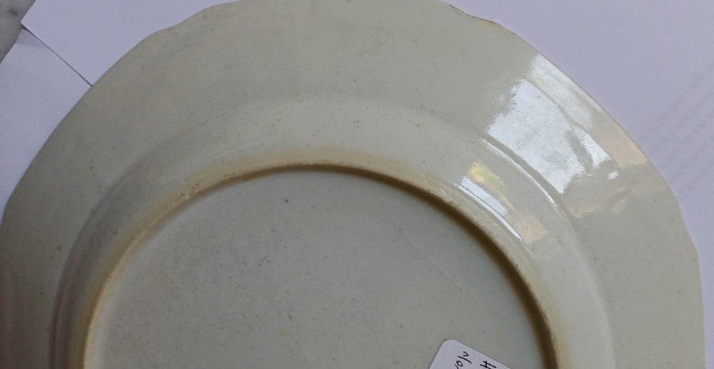 An octagonal 18th-century Chinese export porcelain plate decorated with a central heraldic coat of arms, floral sprays, and a green patterned border. View XVII