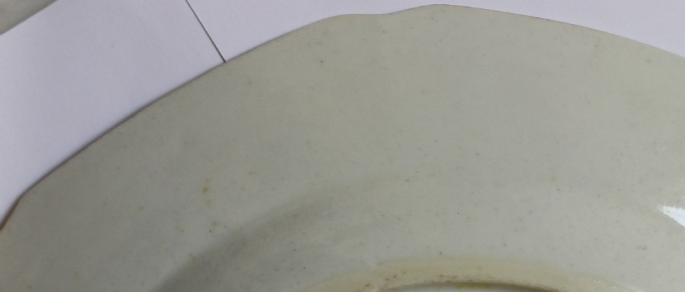 An octagonal 18th-century Chinese export porcelain plate decorated with a central heraldic coat of arms, floral sprays, and a green patterned border. View XX