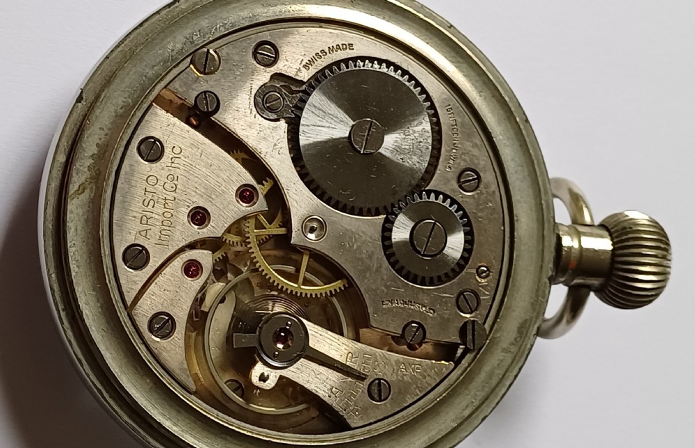 An open-face WW2 military pocket watch featuring a white enamel dial with Roman numerals, a subsidiary seconds dial, and a coin-edge bezel. View XI