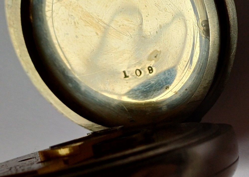 An open-face antique pocket watch featuring a silver-coloured metal casing, cream enamel dial with black Roman numerals, and a gold-toned winding crown. View X