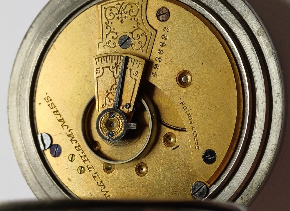 An open-face antique pocket watch featuring a silver-coloured metal casing, cream enamel dial with black Roman numerals, and a gold-toned winding crown. View XIV