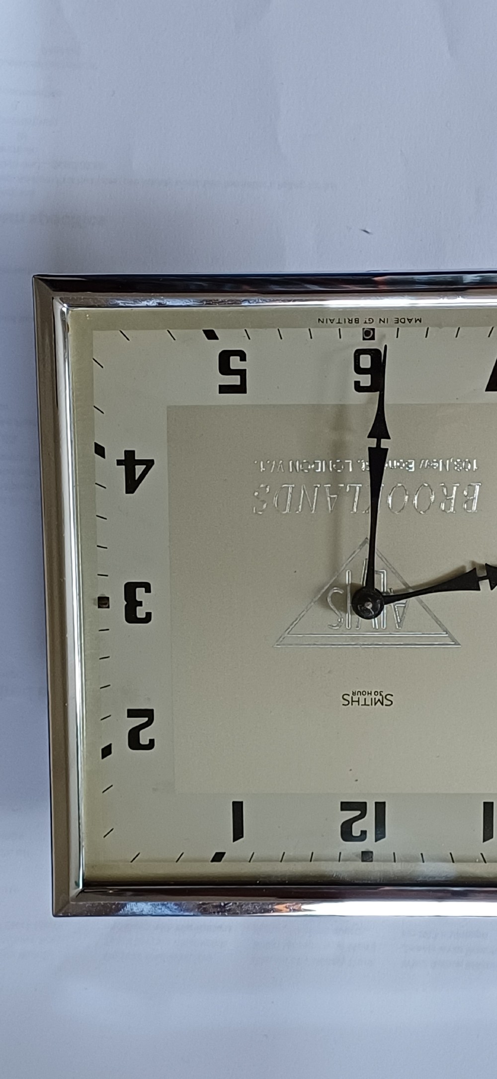A square mid-century chrome desk clock featuring a cream dial with black Arabic numerals and embossed Alvis and Brooklands branding. View III