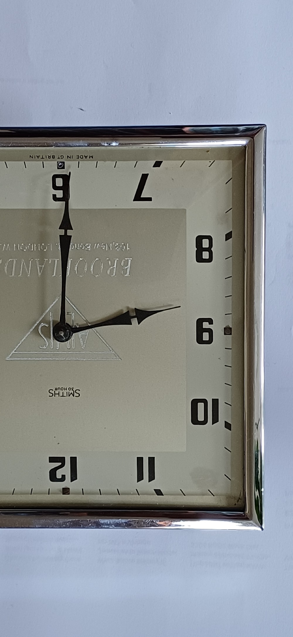 A square mid-century chrome desk clock featuring a cream dial with black Arabic numerals and embossed Alvis and Brooklands branding. View IV
